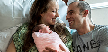 Mom and dad with new born baby, wearing a SANE company shirt