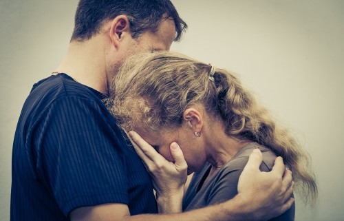 An image of a man hugging and comforting a woman who is upset.