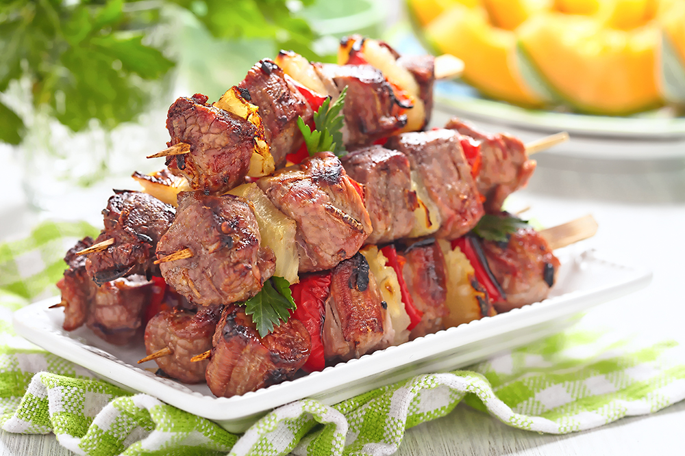 An image of grilled kebabs with red pepper and pineapple on a plate.