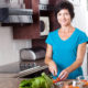 An image of a middle-age woman chopping vegetables in the kitchen.