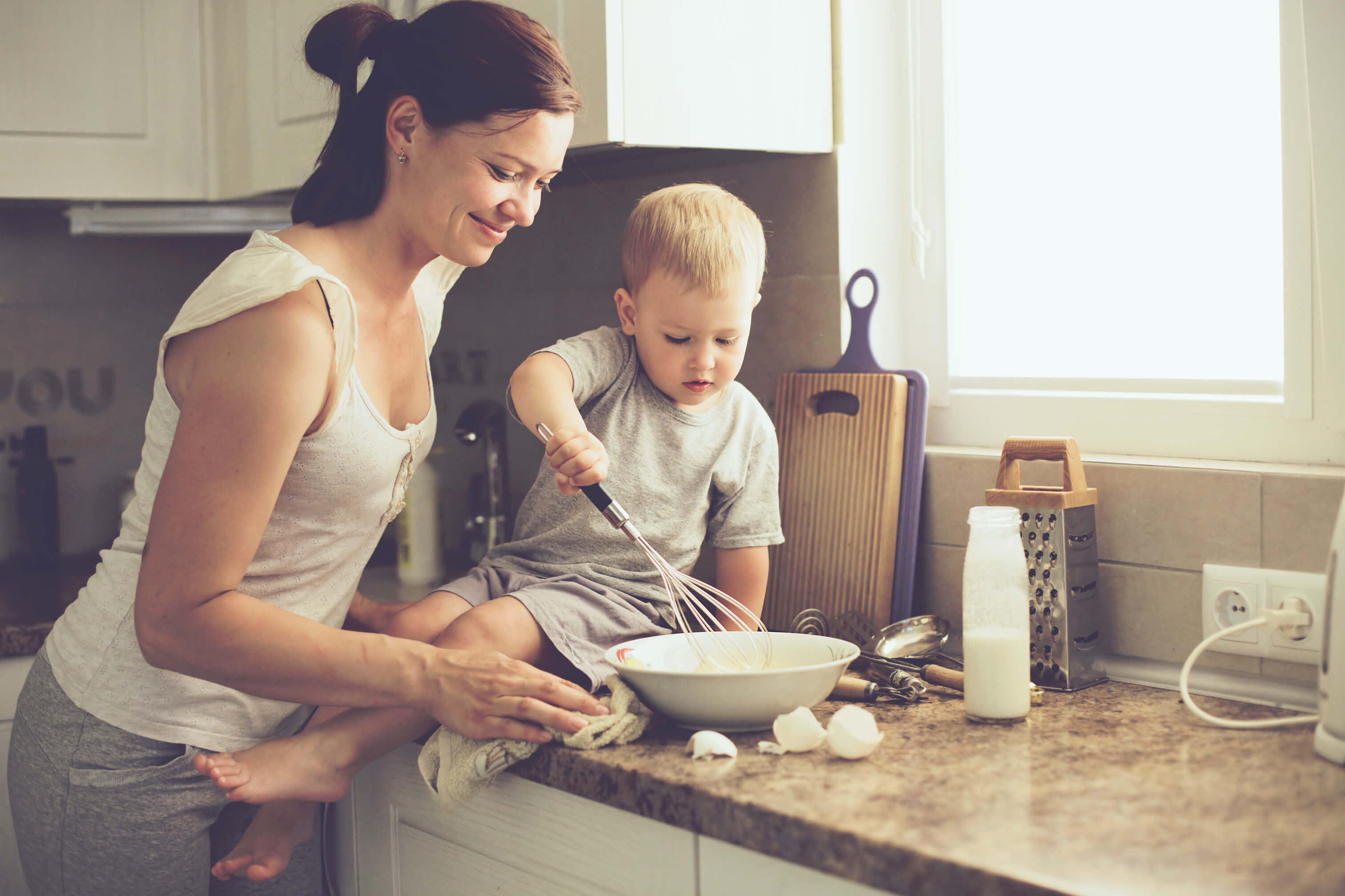 An image of a mother with her two-year-old child cooking in the kitchen.