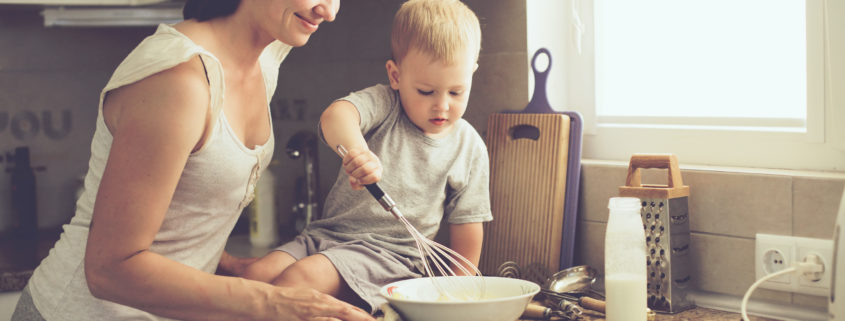 An image of a mother and her two-year-old so cooking in the kitchen.