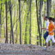 An image of a man and woman jogging on a path through the forest.