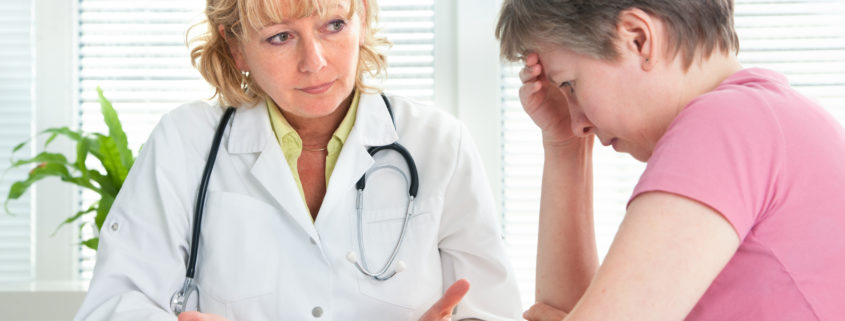 An image of a female doctor reviewing a medical chart with a mature female patient.