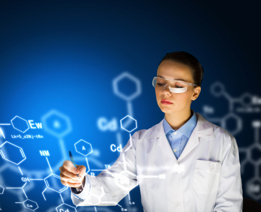 An image of a young researcher in white lab coat working on formulas. 