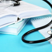 An image of a medical stethoscope with notepad and books on blue background.
