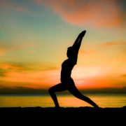 A silhouette of a woman performing a lunge at sunset.