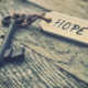 An image of a door key attached to a piece of wood that reads "hope".