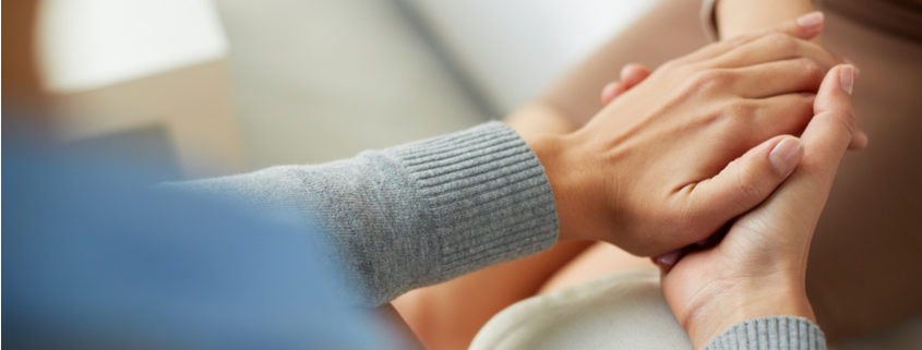 An image of a woman clasping another woman's hand.