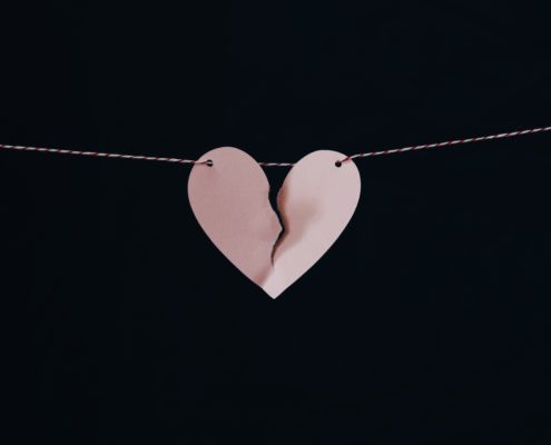 An image of a broken paper heart hanging on a string.