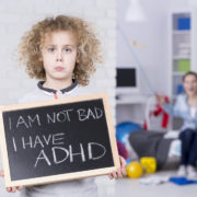 An image of a sad boy holding a small chalkboard that reads, "I am not bad. I have ADHD". Shouting mother is in background.