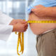 An image of a doctor measuring an obese man's bulging stomach.