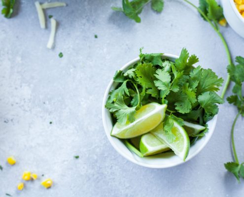 An image of a bowl of lime slices and mint leaves on a table.