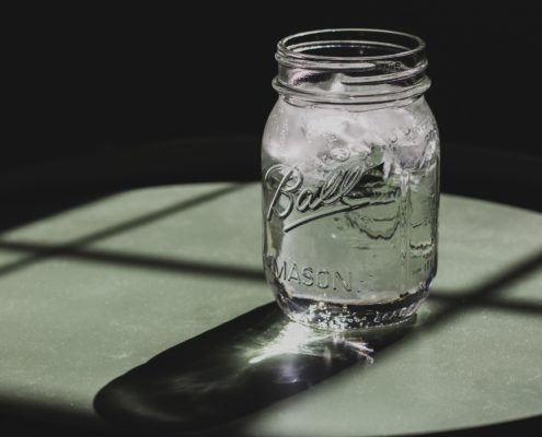 A Mason jar of water with a white toxic cleaning powder on top.