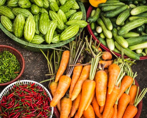 An image of health foods on a table, such as carrots, cucumbers, and peppers.