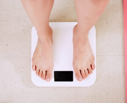 An image of a woman standing on a bathroom scale.