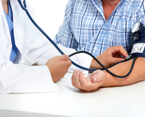 An image of a medical professional checking a man's blood pressure. 