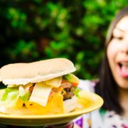 An image of a woman happily looking at a huge hamburger sandwich.