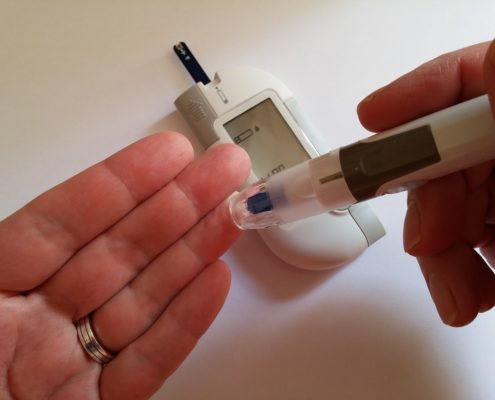 An image of a hand pricking a finger with a glucose meter. 