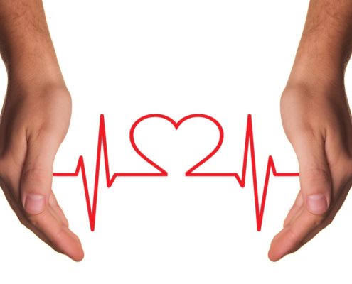 Male hands holding a red line drawing of a heart and EKG lines. 