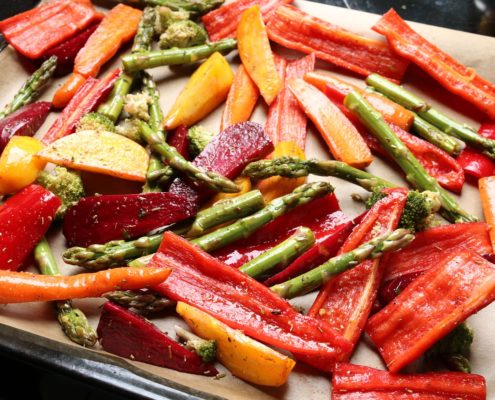 An image of a baking sheet with bell peppers and asparagus. 