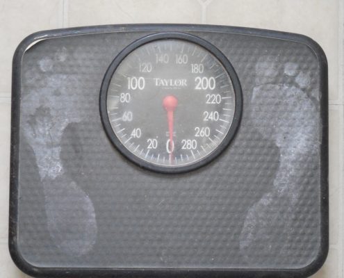An image of a bathroom scale with whiteish foot prints on either side.