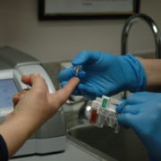 An image of a healthcare worker pricking a patient's finger to test blood glucose level.