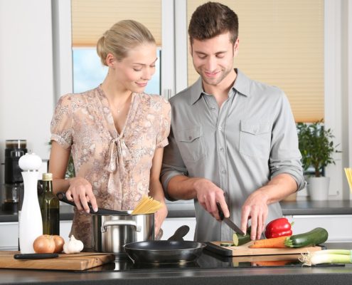 An image of a young man and woman cooking in the kitchen together.