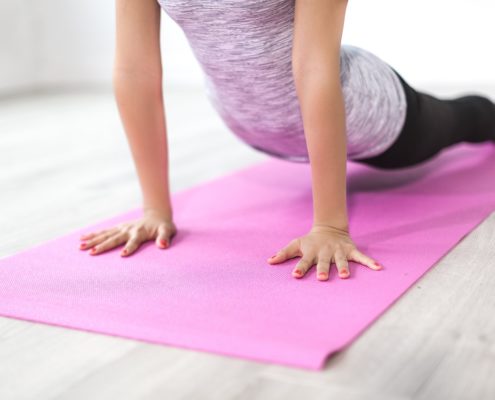 An image of a woman doing a yogic cobra pose by straightening her arms, and lifting her stomach and thighs off the mat.