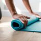 An image of a woman rolling up a yoga mat on the floor.