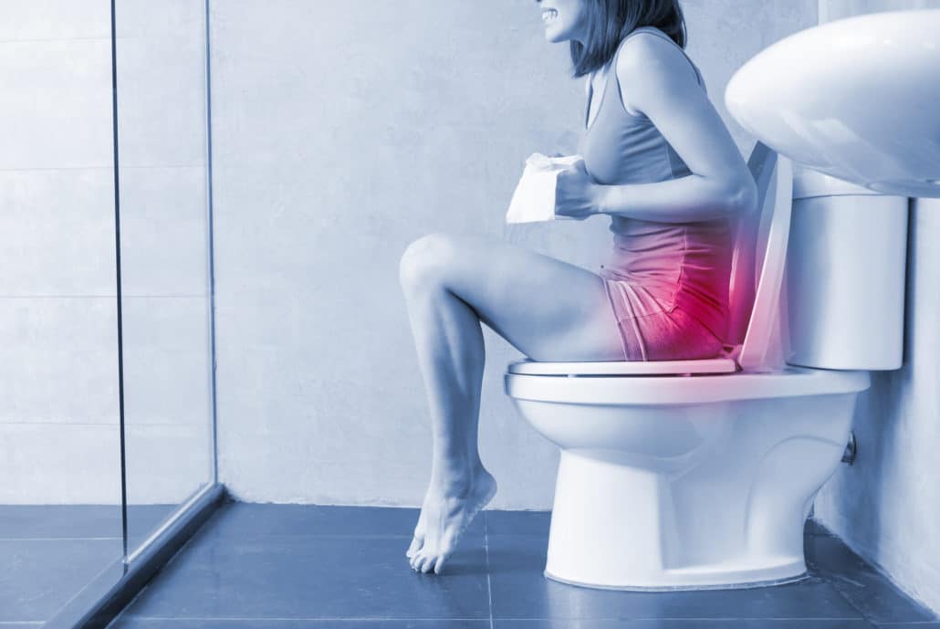 An image of a woman sitting on a toilet in pain due to constipation. 