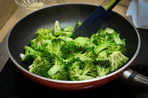 An image of broccoli in a frying plan on the stove.