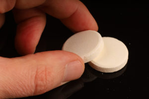 An image of make finger picking up two antacid tablets.