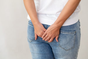 An image of the back of a woman wearing jeans, her hands holding her backside.