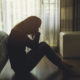 An image of a woman's profile sitting on the floor, face in hands.
