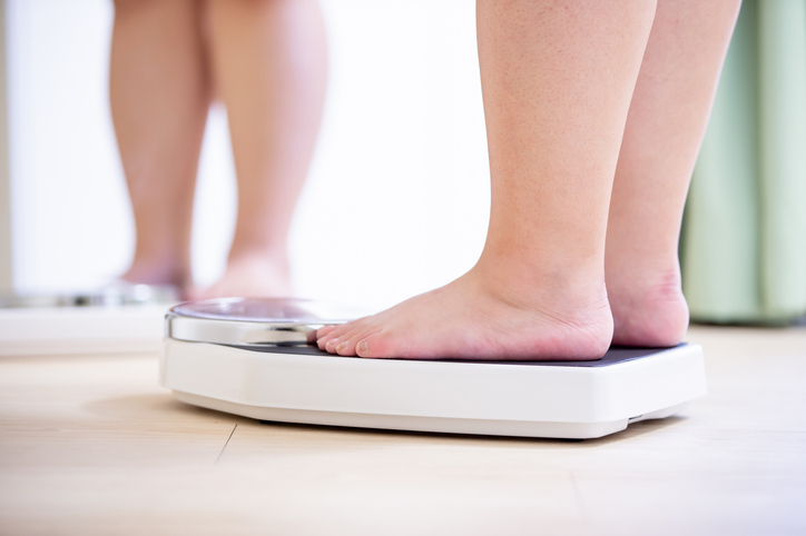 An image of an obese woman standing on a bathroom scale. 