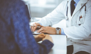 A cropped image of a doctor consulting with his female patients.